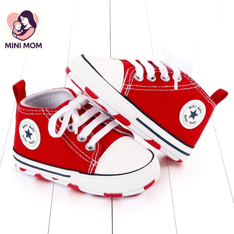 Red high-top sneakers with white laces on a light wooden floor, featuring the Mini Mom logo.