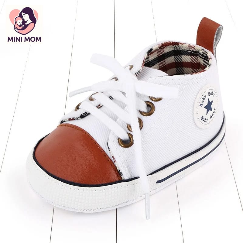 White baby shoe with brown accents on a white background, featuring the Mini Mom brand.