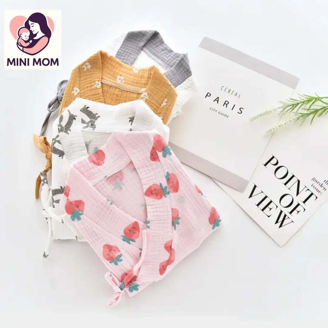 Baby clothing set with a yellow shirt, white bib with animal print, and pink blanket with strawberry pattern on a white background.