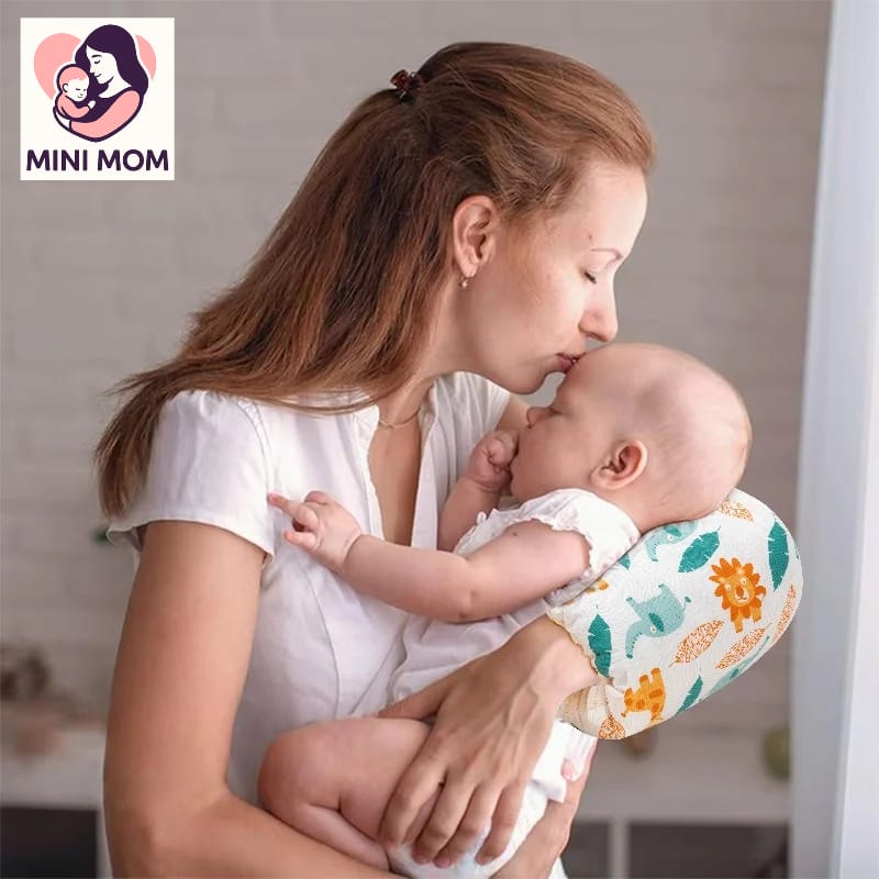 Woman holding a baby with a floral-patterned support pillow, featuring the 'MINI MOM' brand.