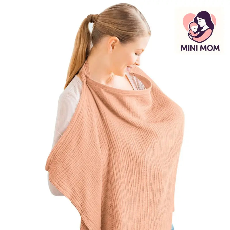 Woman wearing a peach-colored baby wrap with 'Mini Mom' logo in the corner