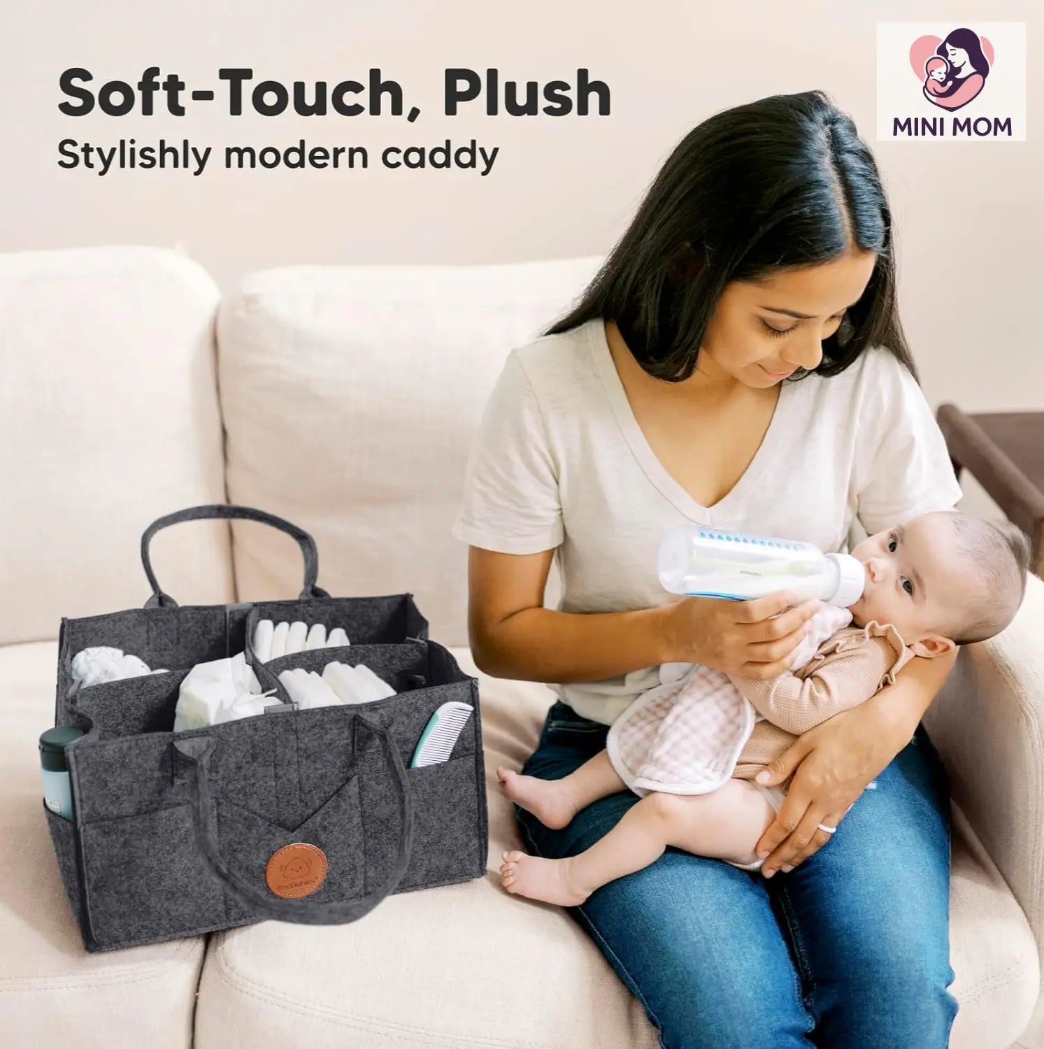 Woman holding a baby and a soft-touch, plush caddy on a couch with 'MINI MOM' branding.